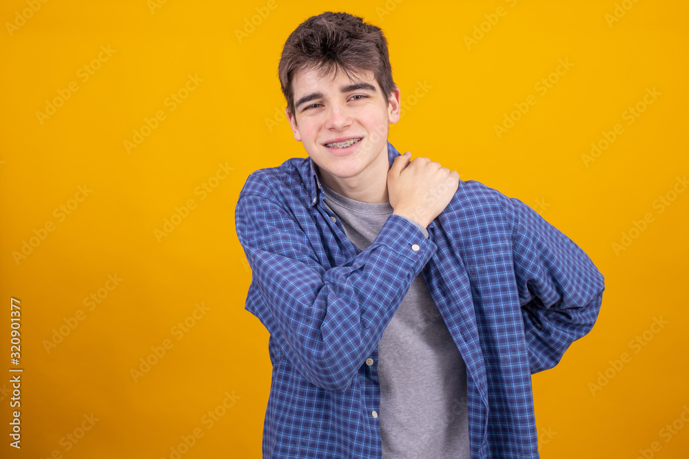 Poster young teenager or student boy isolated on color background with back or neck pain