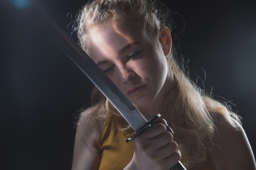 A beautiful young girl with a Japanese sword in her hands, a blonde in round dark glasses with a cold weapon in her hands