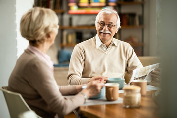 Happy senior man communicating with his wife during breakfast at home.