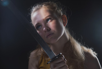 A beautiful young girl with a Japanese sword in her hands, a blonde in round dark glasses with a cold weapon in her hands