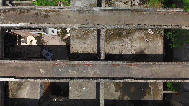 drone video birds eye view of a freerunner jumping over some abandoned buildings and finishing with a sideflip