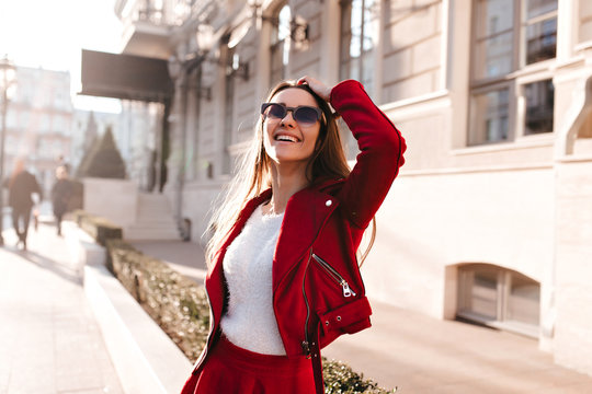 Refined caucasian girl in sunglasses looking up. Outdoor photo of charming white lady in red clothes posing in sunny morning.