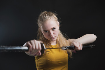 A beautiful young girl with a Japanese sword in her hands, a blonde in round dark glasses with a cold weapon in her hands
