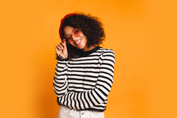 Portrait of happy young black woman laughing against yellow wall. Blissful lovable woman with...