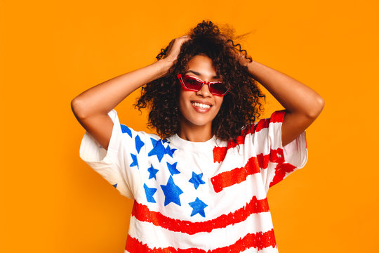 Happy young african  woman with t-shirt with national flag of USA at yellow background. American dream. happy young multicultural girl joyful and excited. Work and travel. Student girl. 