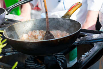 Cheff preparing delicious shripm dish in a frying pan.