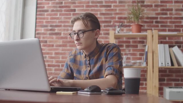 The student is typing on a laptop, drinking coffee and smiling at the camera. A freelancer is working on a laptop, drinking a latte and smiling at the camera
