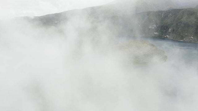 Aerial flies through fog and reveals Cuicocha Islands, Otavalo Ecuador.