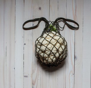 Cauliflower in a string bag on a light background, image of a rabbit
