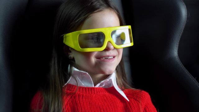 Little girl watching exciting movie at cinema with 3D glasses