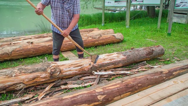 Slow motion shot of a traditional raftman wood chiselling beside Drava River in Slovenia