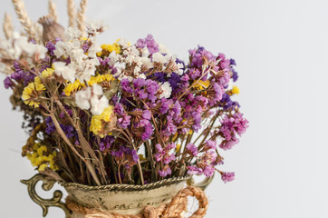 Still life in rustic vase with dry yellow and violet wildflowers. Isolated on white background. Copy space.
