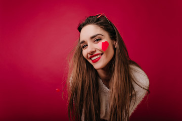 Pleased white girl with brown hair smiling to camera. Indoor photo of caucasian long-haired lady having fun during photoshoot in valentine's day.