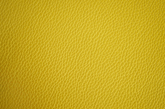Leather texture close up. Yellow fashionable background, top view. Stylish wallpaper of golden color. Rough surface.