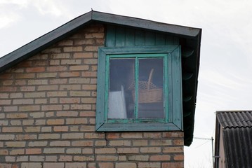 old brown brick loft with a large green wooden window against a gray sky