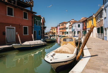 Fototapeta na wymiar Colorful houses in Burano along canal and boats, Venice, Italy