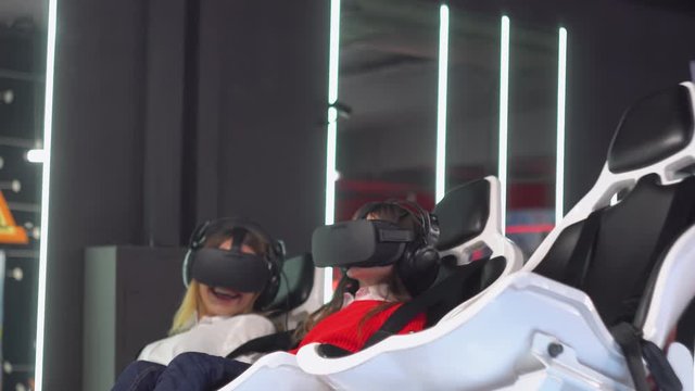 Woman and little girl with VR glasses rides virtual reality simulator