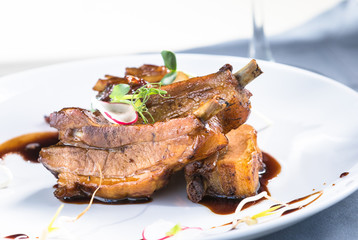 Ribs in honey onion glaze on a white plate close up