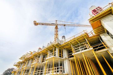 Fototapeta premium High-rise building under construction. The site with cranes against blue sky