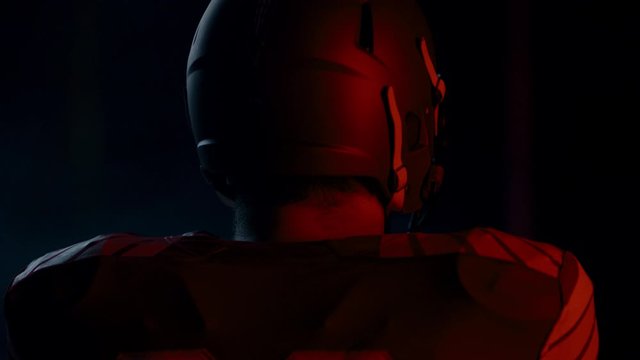 CU Portrait of American football player in protective uniform posing against bright flashing lights. Shot on ARRI Alexa Mini 60 FPS slow motion