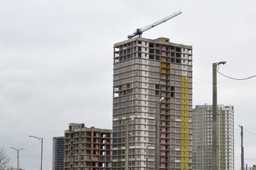 Construction of large modern monolithic frame houses, buildings using industrial construction equipment and large high cranes. Construction of the building in the new micro district of the city