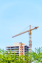 High-rise building under construction. The site with cranes against blue sky