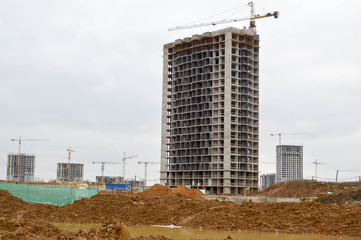 Construction of a new microdistrict with high houses, new buildings with developed infrastructure with the help of large industrial cranes and professional construction equipment in a big city