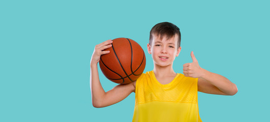 Young basketball player posing with a ball in his hand isolated on blue background