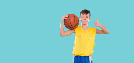 Young basketball player posing with a ball in his hand isolated on blue background
