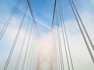 Architectural detail of suspension bridge on foggy day