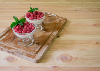 Italian dessert panna cotta with fresh raspberry served in glass bowls on cutting board. Selective focus.