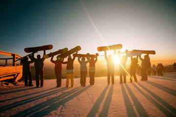 Group of skiers and snowboarders at sunset. Ski resort concept