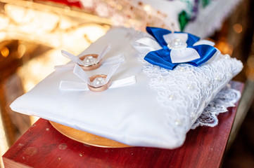Pair of golden wedding rings on the white pillow