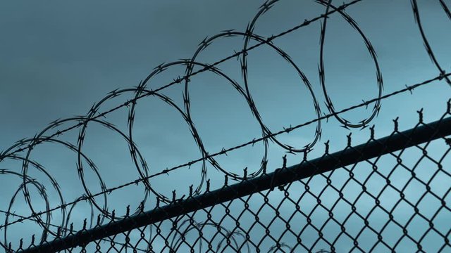 Time-lapse of prison razor wire and barb wire border perimeter. 