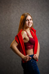 Girl tries on a red sweater on a gray background