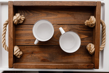 Fototapeta na wymiar Top flat view of two white empty cups on rustic wooden tray and background. Cozy home, lovely breakfast with beloved