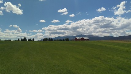 Green Grassy Knoll with Red Barn Over Yonder