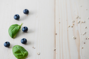 Delicious basil and blueberries on a light wood background