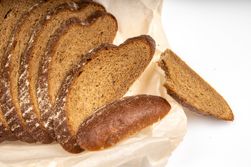Rye bread cut in pieces lying on the baking paper on a white background