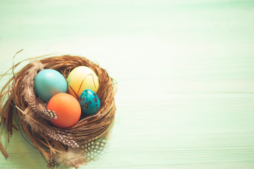 Neste with colorful Easter eggs on wooden table, closeup