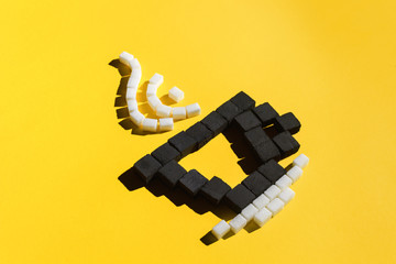 Cup of coffee with steam made with coal and sugar cubes on yellow background.