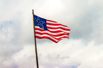 wavy great star flag with stars in the shape of a star waving proudly in a sky of a mass of clouds