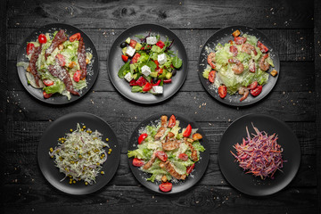 Set from different tasty,  nutritious salad of greens, cabbage, peas, carrots. Quick and easy to cook. Vegetarian food. Octoberfest party dinner. Festive table with delicious food on black boards