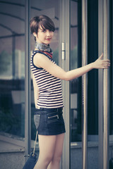 Happy young fashion woman with handbag next to mall door