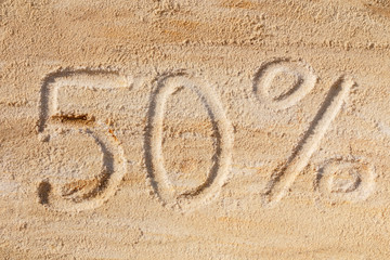 Inscription 50% on the sand, concept for discount.