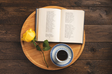 Romantic concept. Wooden tray with open book, rose, cup of coffee, on wooden background. Flat lay, top view, copy space.