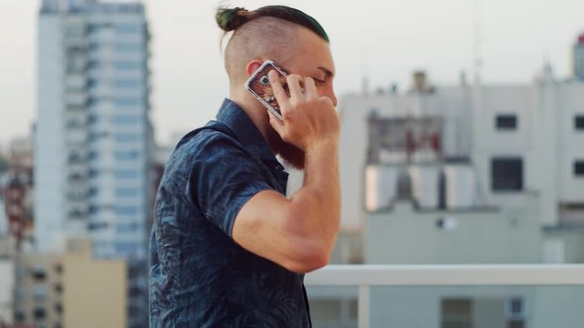 Handsome man with short colored hair on the terrace overlooking the city