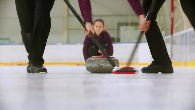 Curling - leading granite stone on the ice and rubbing the ice before the stone