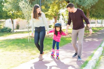 Parents At Park Guiding Daughter To Skate