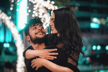 Happy woman is on her boyfriend's back, looking at her, smiling.